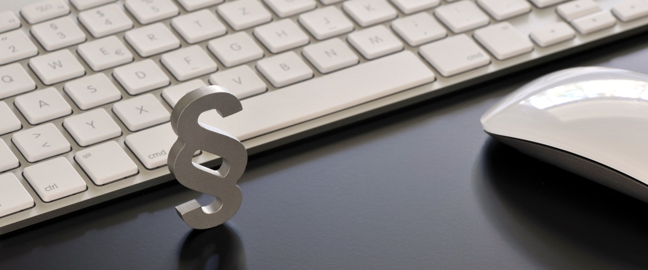 Weißes Paragrafenzeichen vor Computertastatur, daneben Computermaus