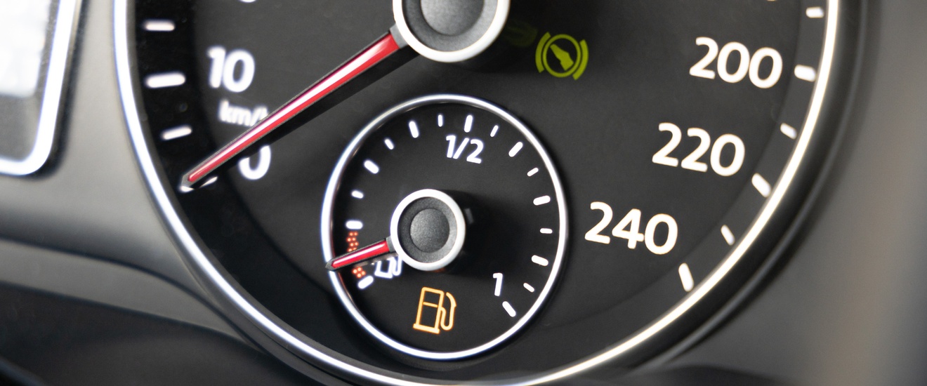 Detailansicht eines Cockpits in einem Auto mit rot leuchtenden Warnanzeigen für den Tankstand sowie für das Anschnallen