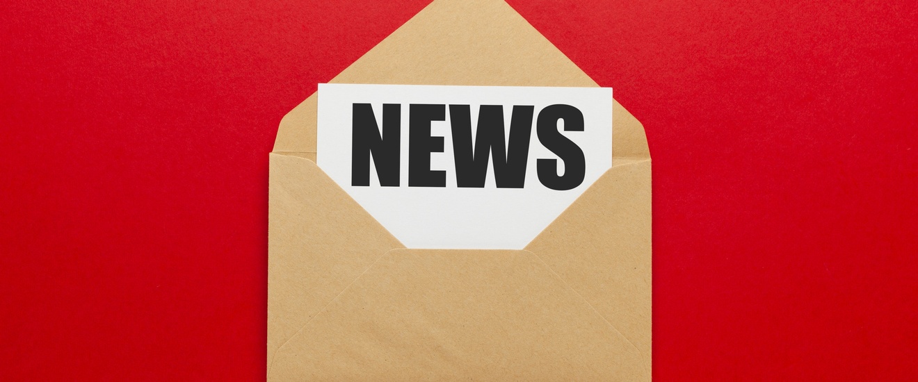 Geöffneter hellbrauner Briefumschlag mit weißem Blatt und Aufschrift News vor einem roten Hintergrund