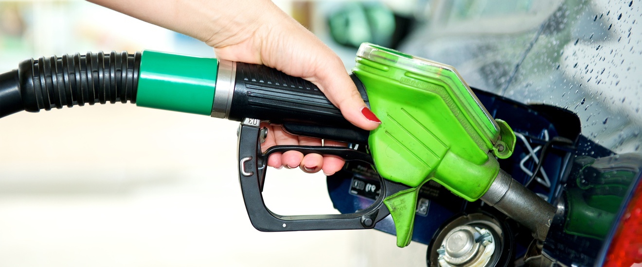 Hand hält Tankstutzen in die Öffnung eines Autotanks