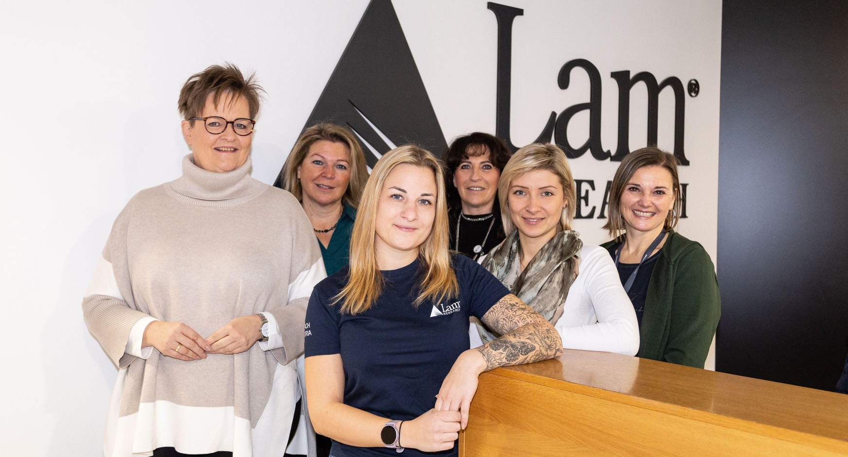 Eine Gruppe von Frauen vor einem Firmenlogo.