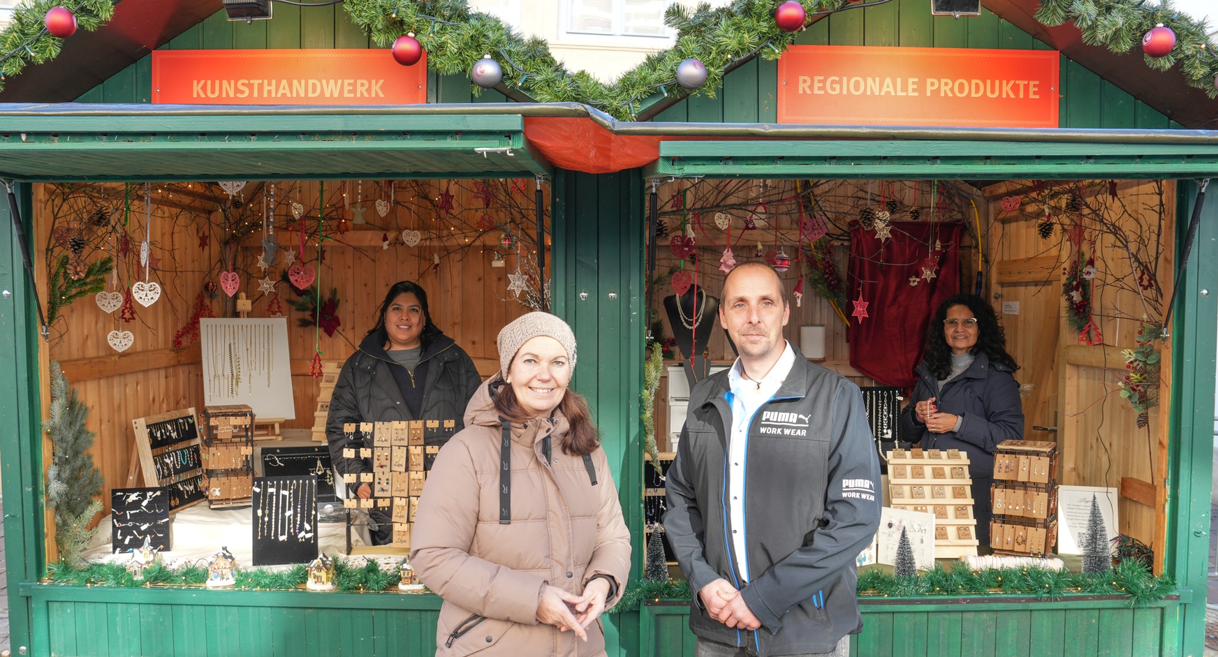Melanie Eckhardt (Obfrau des burgenländischen Markthandels) und Benjamin Fink (Vorsitzender der Fachvertretung des Kunsthandwerks) vor dem Stand von Priscilla Otero Crisanto (l.) und Luz Crisanto Calle de Feymann am Eisenstädter Christkindlmarkt 
