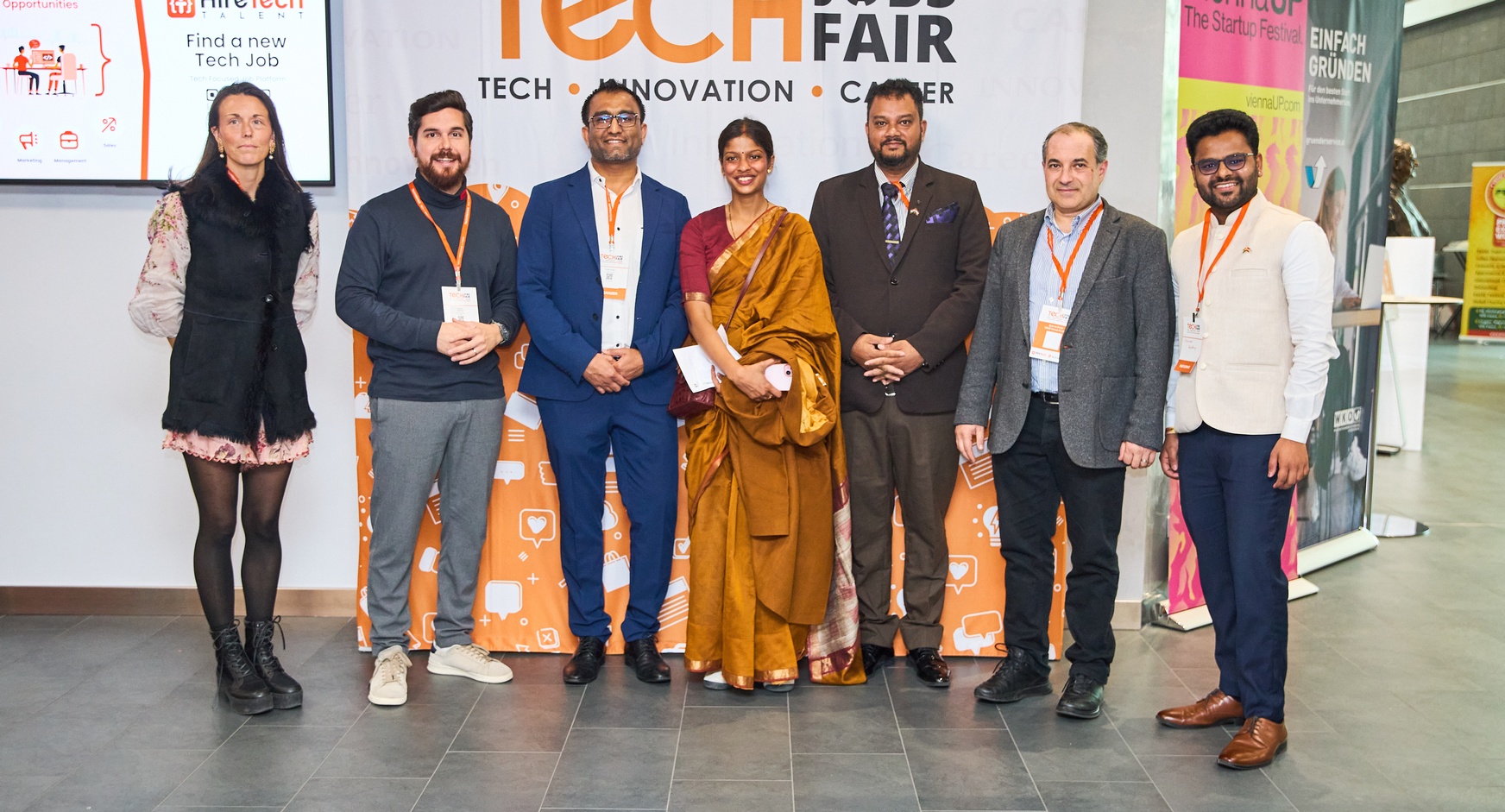 Personen stehen nebeneinander, hinter ihnen ist ein Roll-up mit dem Schriftzug Tech Fair