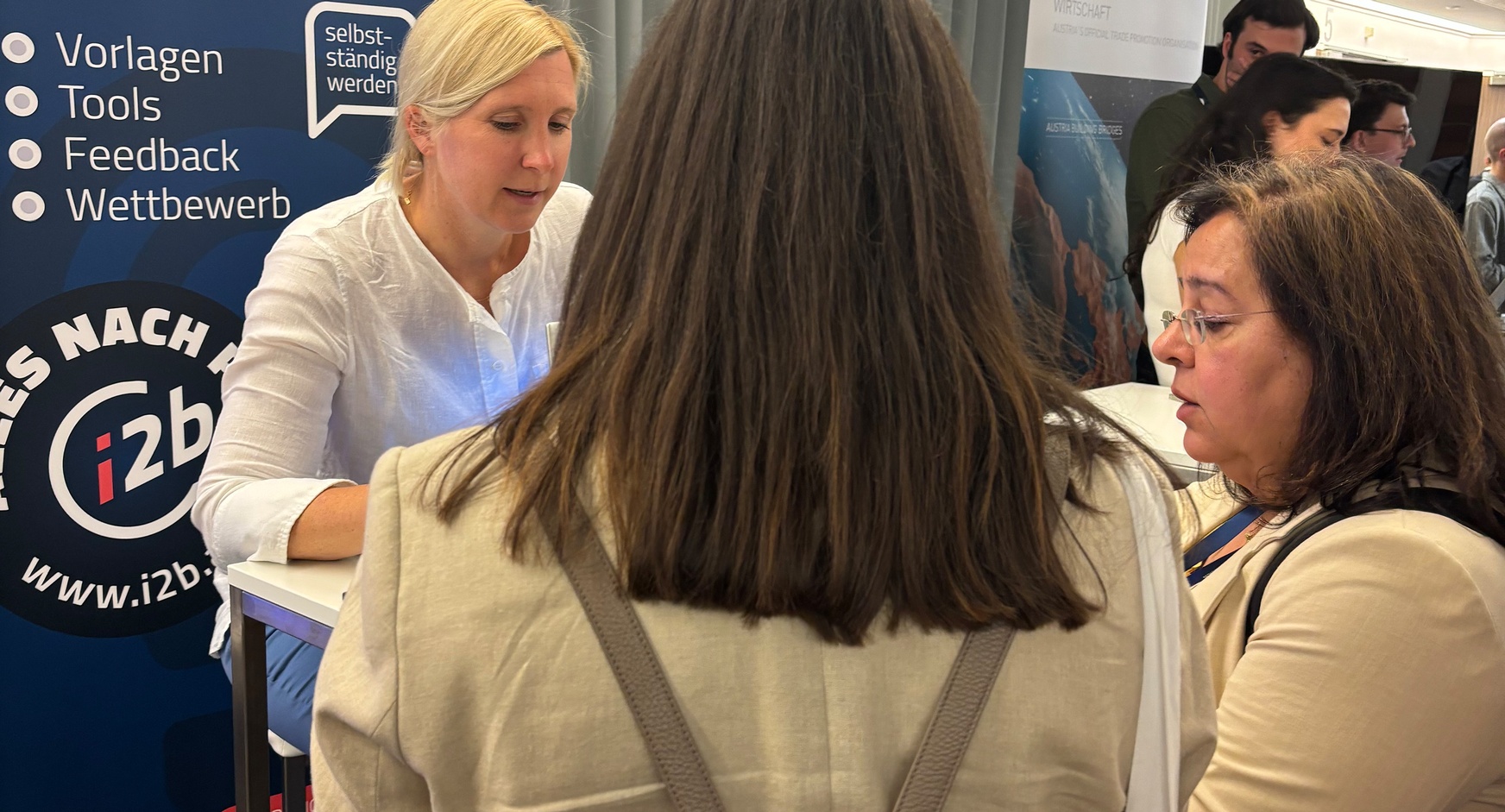 Drei Personen stehen an einem Check-In-Schalter eines Events