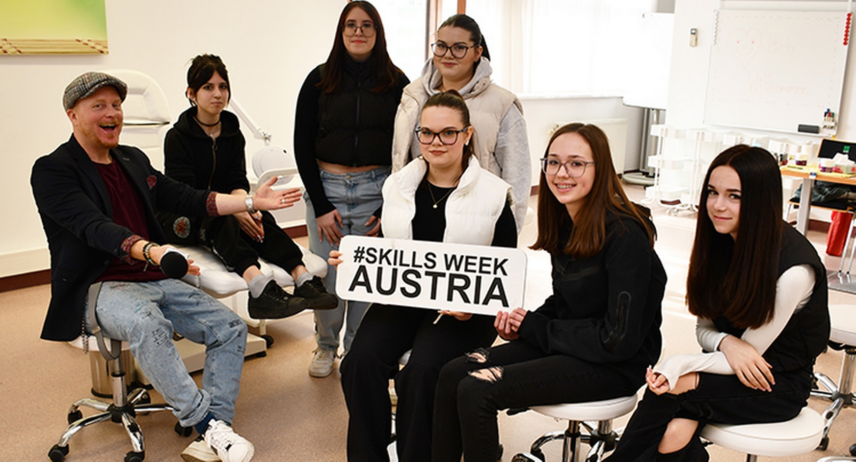 Mehrere Personen sitzend, eine hält Schild mit Schriftzug Skills Week Austria