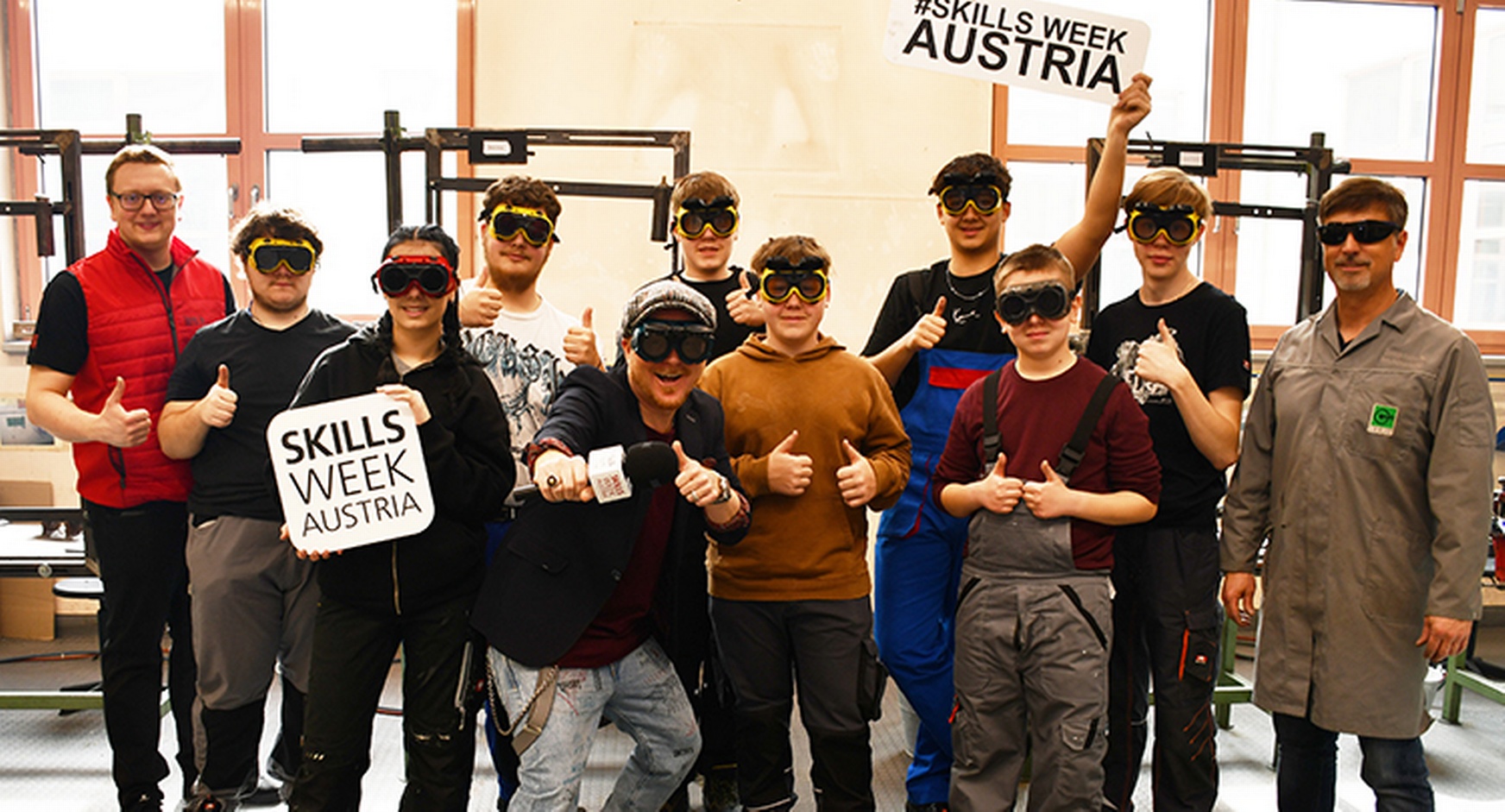 Gruppenfoto mehrerer Personen mit Schutzbrillen, zwei mit Schildern mit Schriftzug Skills Week Austria