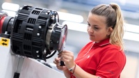 Frau in rotem Poloshirt arbeitet an der Maschine