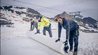 Drei Menschen bei der Arbeit auf einer Schneepiste