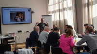 Man sieht mehrere Menschen in einem Seminarraum