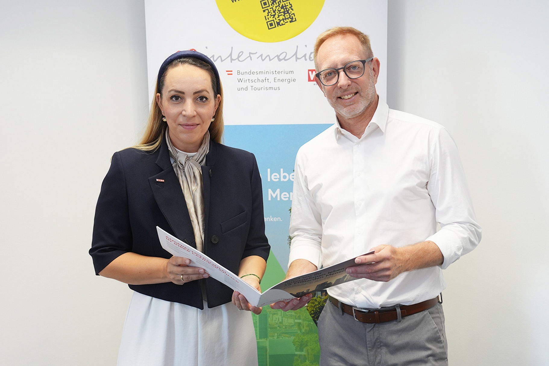 Bundesministerin für Wirtschaft, Energie und Tourismus, Margarete Schramböck, und ein Mann halten Broschüren in Wien.