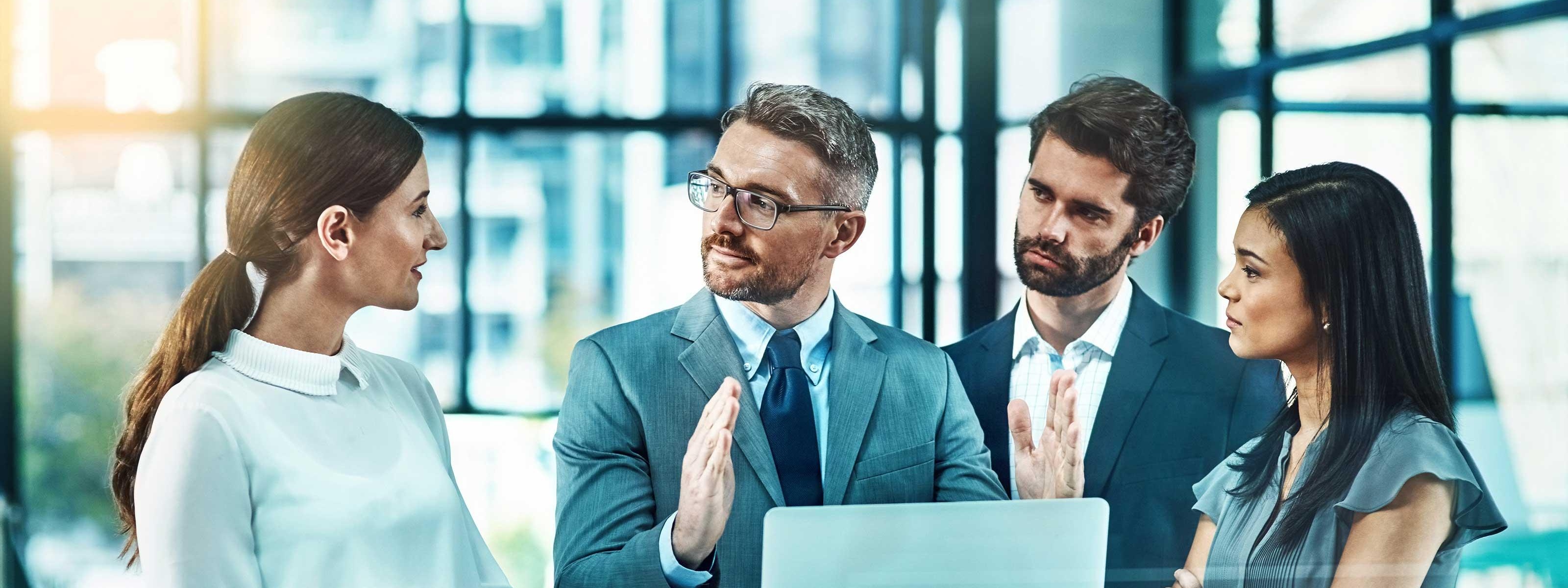 Vier Personen stehen um einen Stehtisch und unterhalten sich