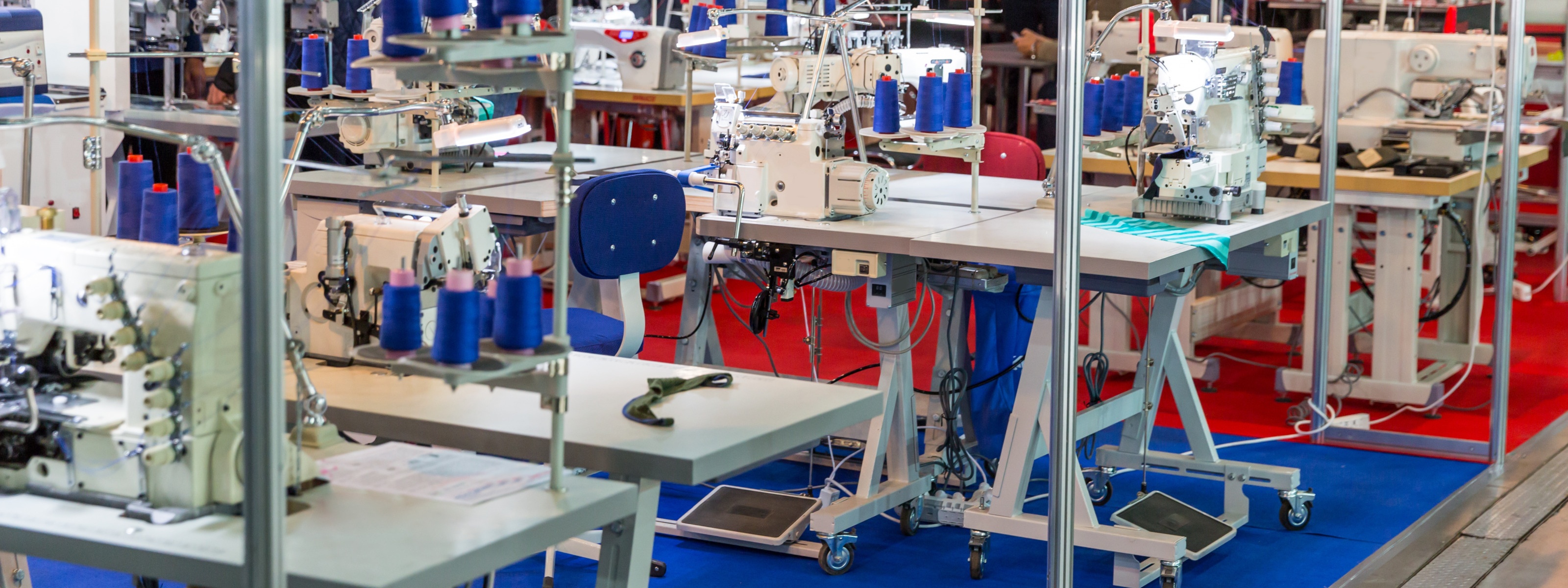 Mehrere Tische mit Nähmaschinen und blauen Stühlen
