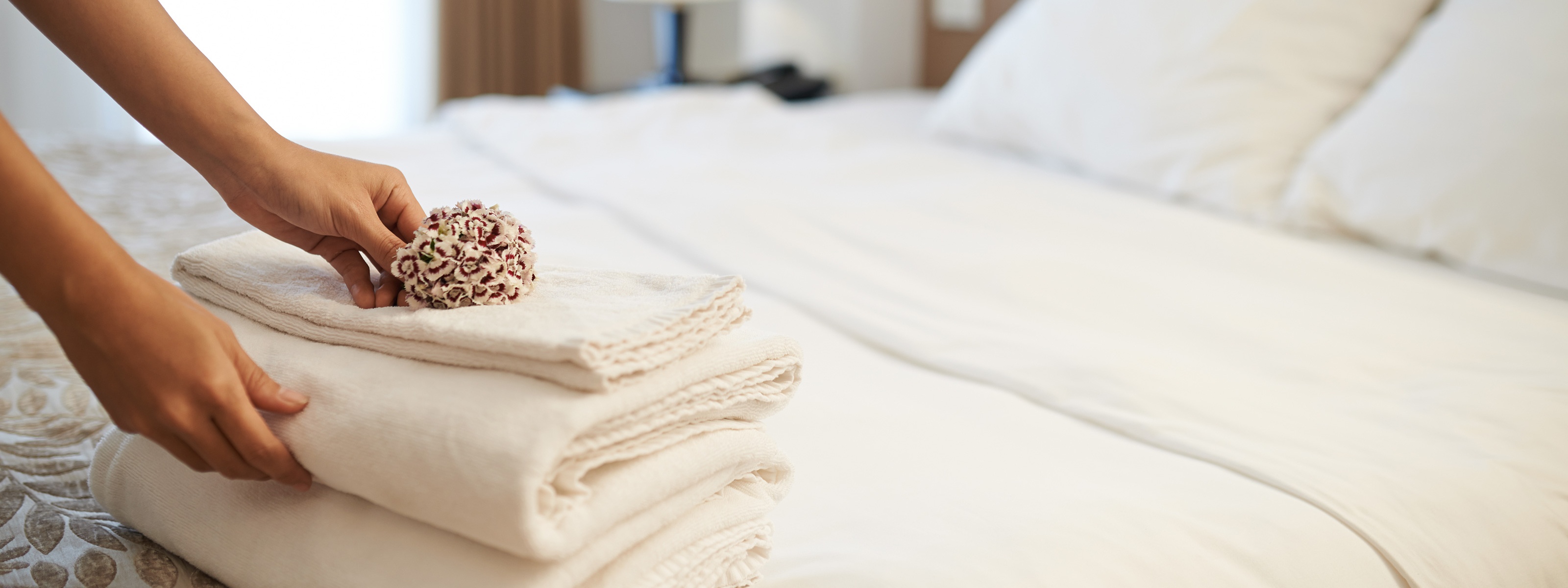 Hotelzimmer mit einem Stapel frischer Badetücher auf dem Bett