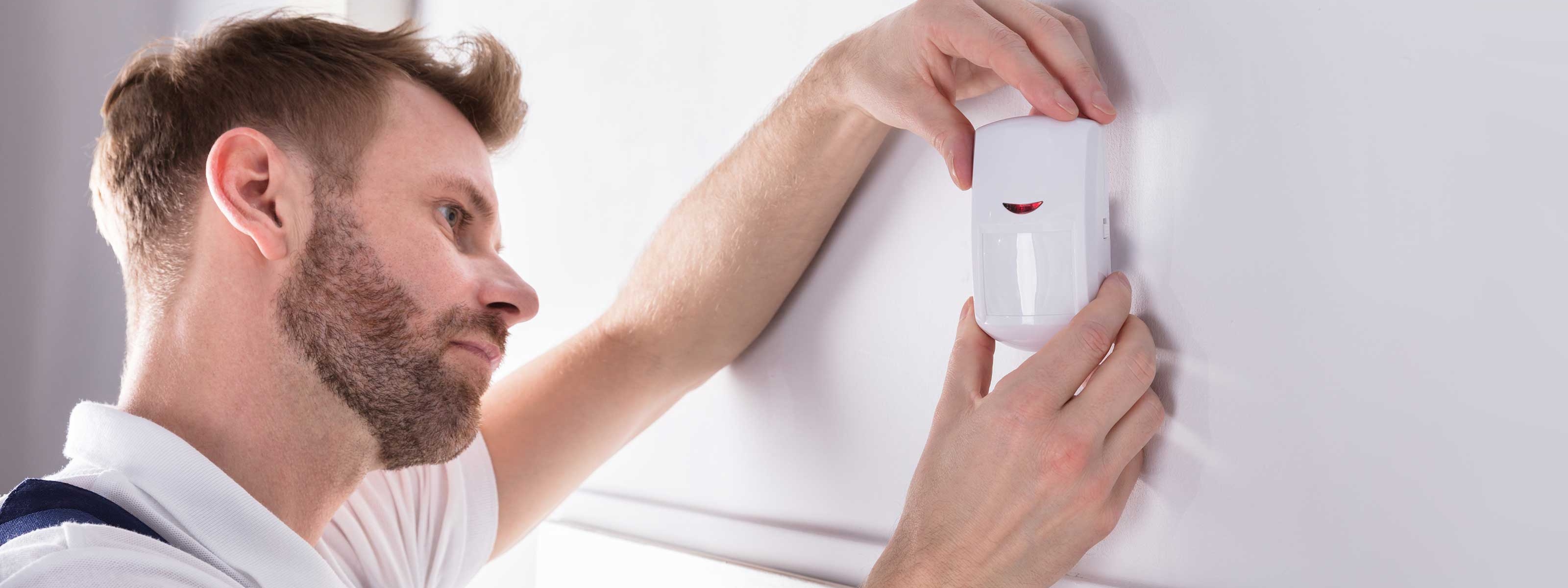 Ein Elektriker montiert einen Bewegungsmelder