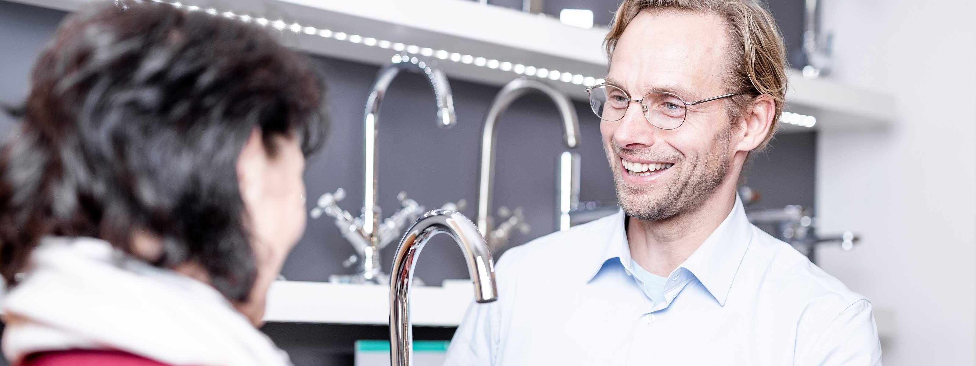 Ein Installateur mit einem Wasserhahn in der Hand bei der Kundeberatung