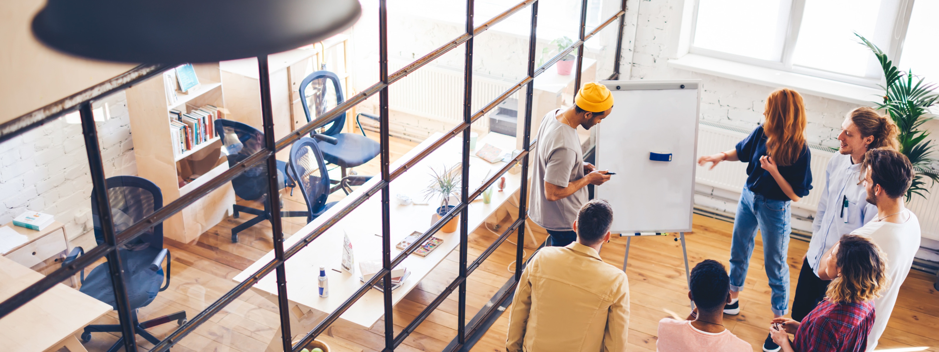 Junges Team beim Brainstorming vor einem Whiteboard in einem offenen Büro
