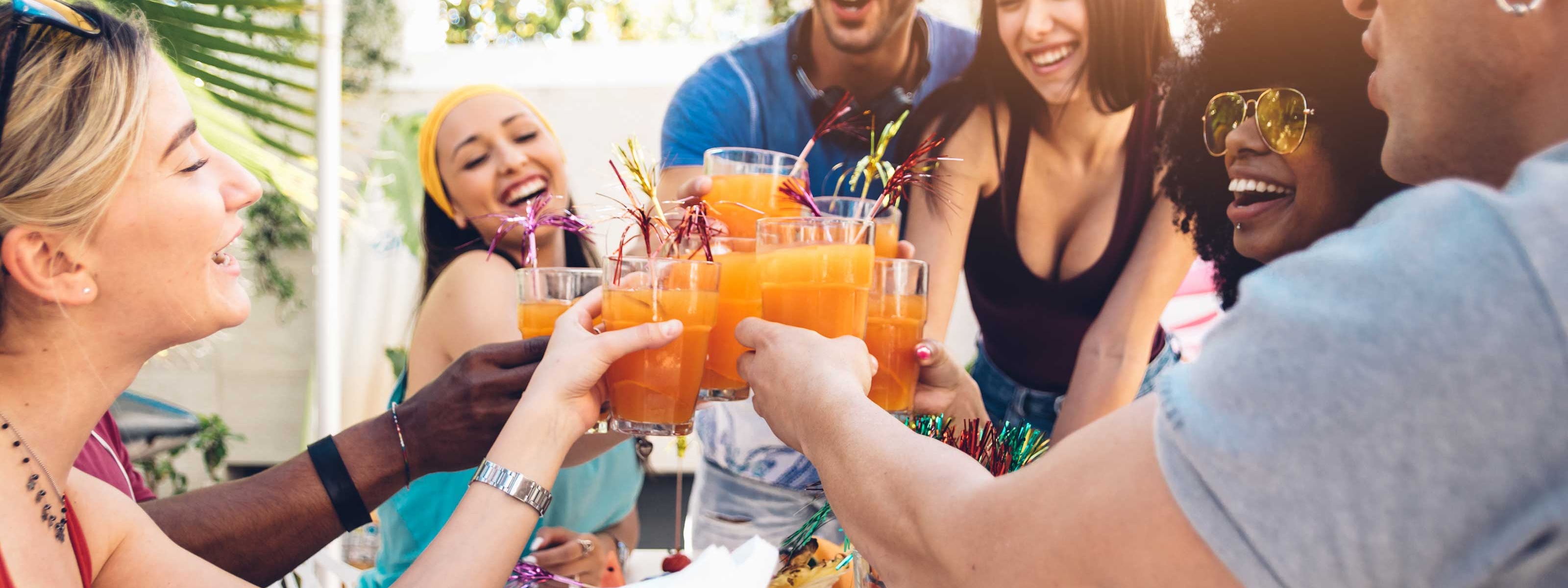 Eine Gruppe von jungen Leuten um einen Tisch prosten sich zu