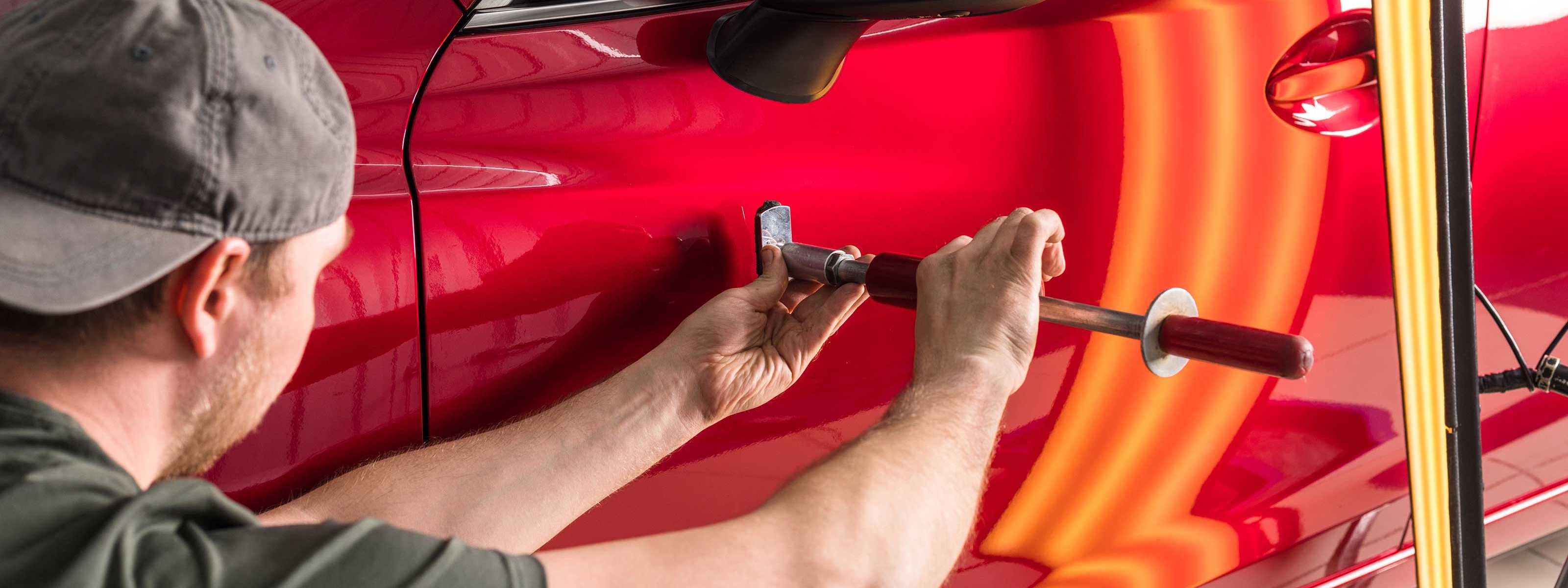 Ein Dellentechniker beim Ausbeulen einer Delle 