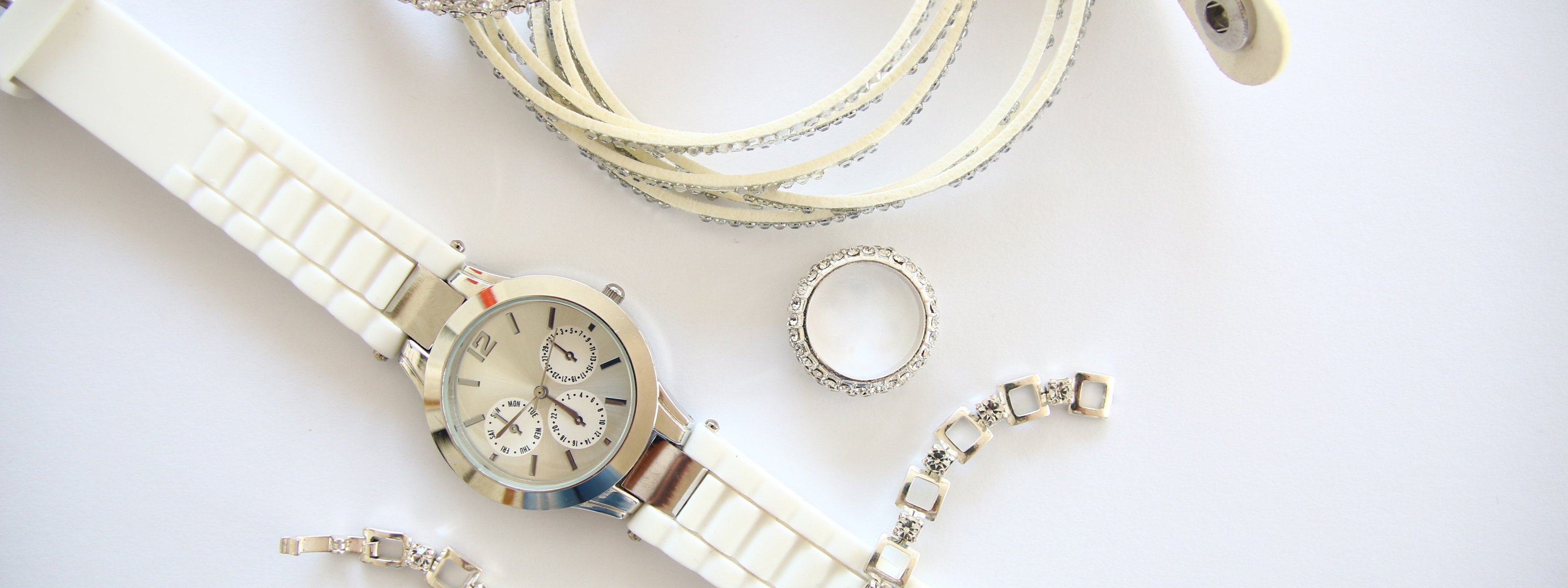 Juwelenarmband über Armbanduhr platziert, ringsum Ring und weitere Schmuckarmbänder