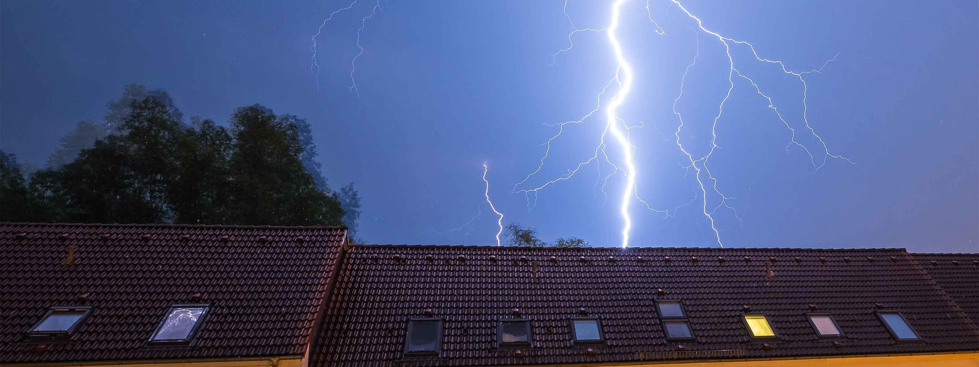 Ein Blitz schlägt hinter einem haus ein.
