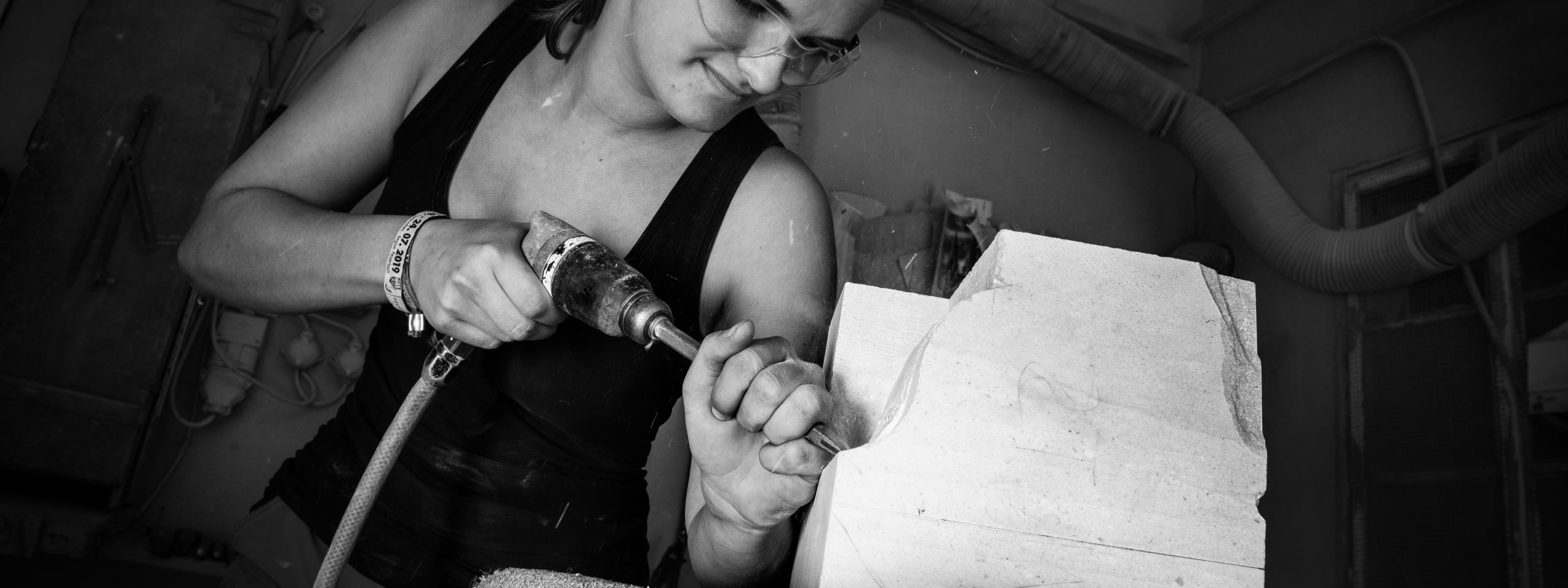 Person mit Schutzbrille bearbeitet einen Stein mit einer Maschine