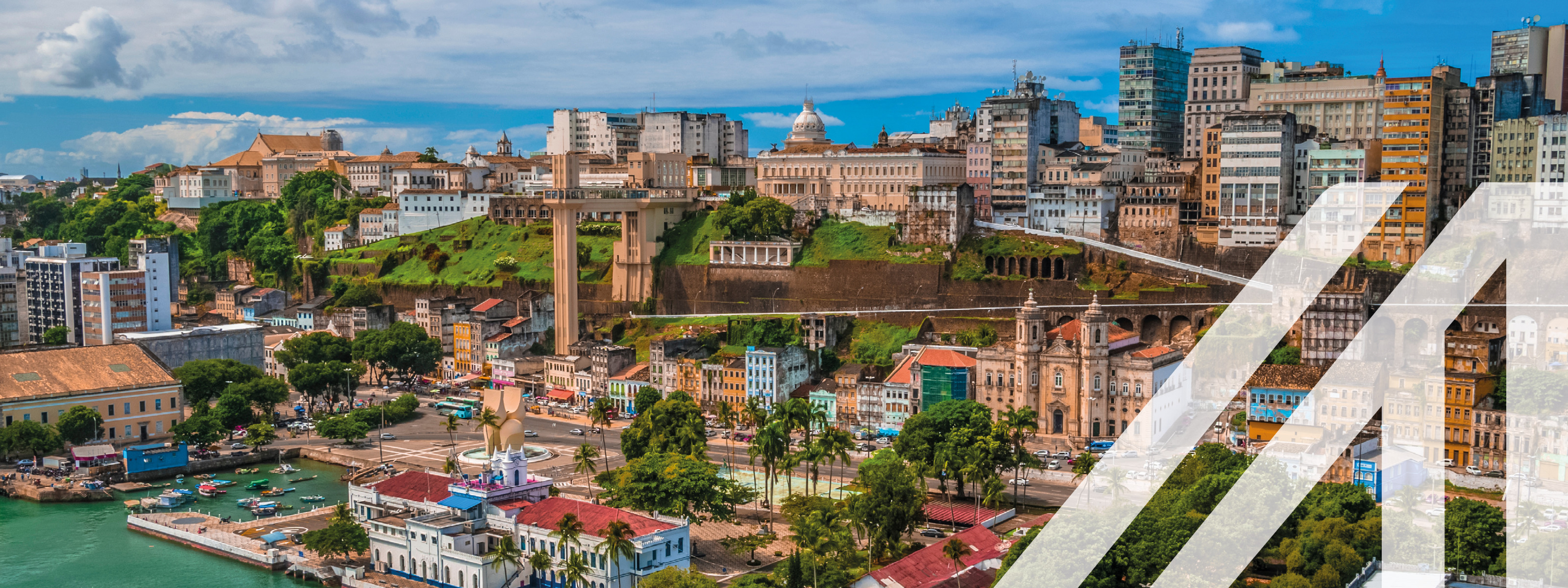 Blick auf den Hafen von San Salvador mit historischen Gebäuden im Kolonialstil, Schiffen und Palmen. Im Hintergrund erheben sich moderne Hochhäuser. 
