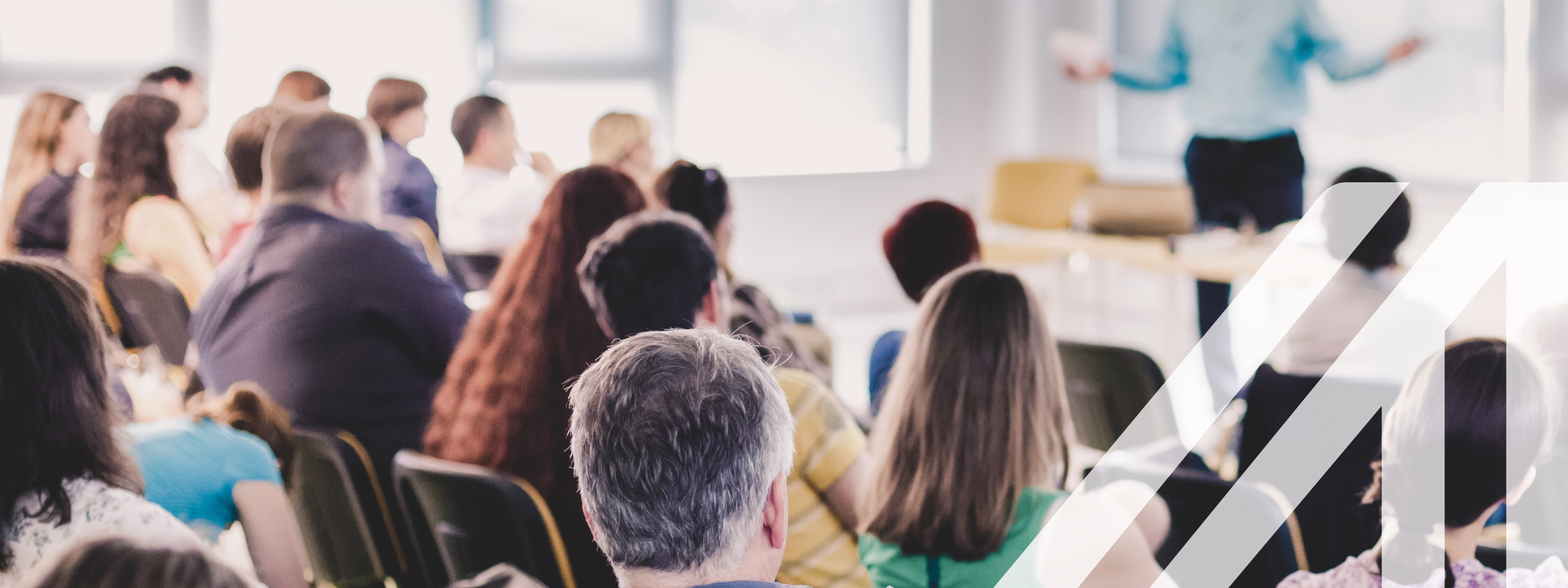 Vortragender vor einem gemischten Publikum von hinten in einem Konferenzsaal. 