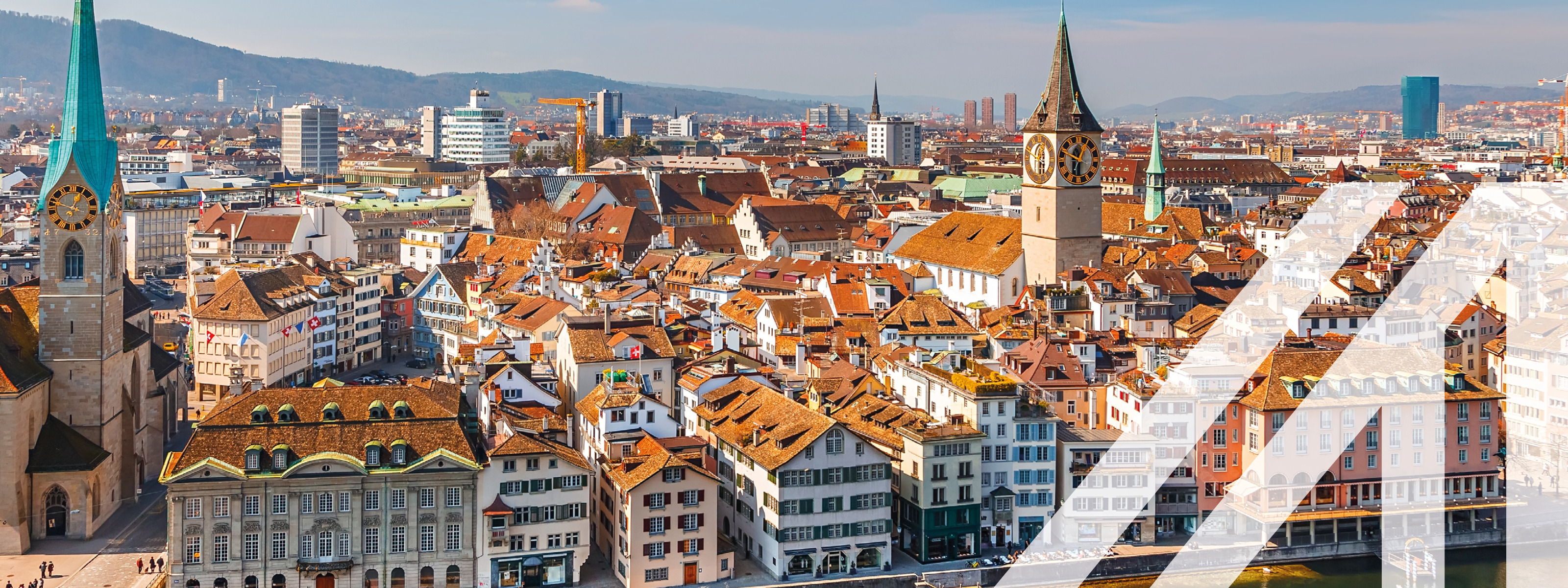 Stadtansicht von Zürich: historische Häuser mit roten Dächern, darunter ragen einzelne Türme hervor, eine Brücke führt über den Fluss. <br />
Über das Bild wurde ein weißes Austria A gelegt.