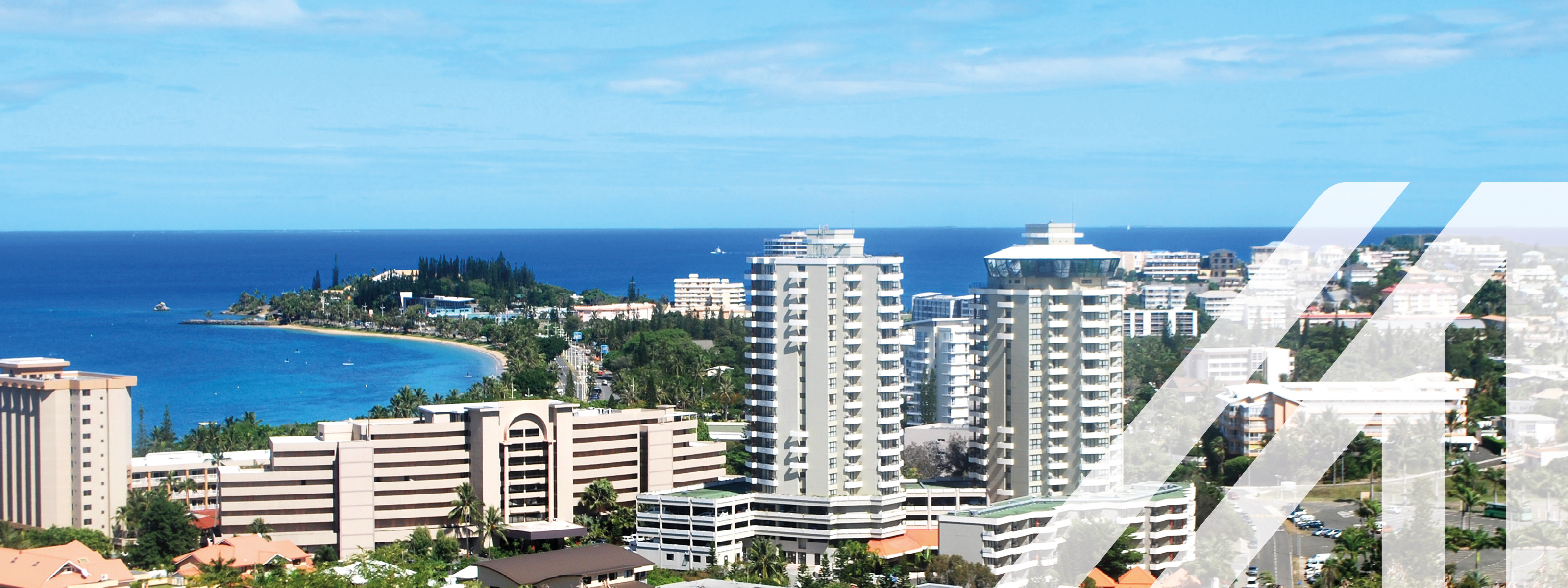 Stadtansicht von Nouméa am Meer gelegen, einheitliche weiße Hochhäuser, darüber blauer Himmel