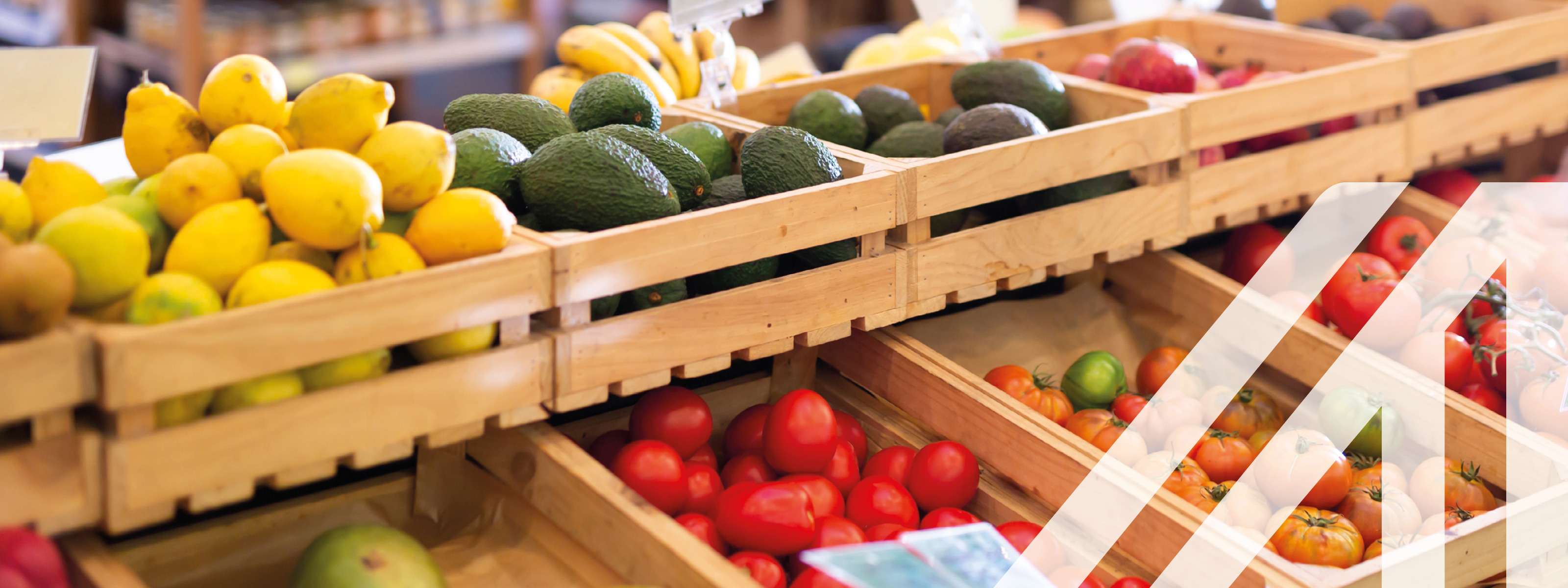 Frisches Obst und Gemüse in Holzkisten auf der Ladentheke in einem Lebensmittelsupermarkt, im Hintergrund sieht man Regale
