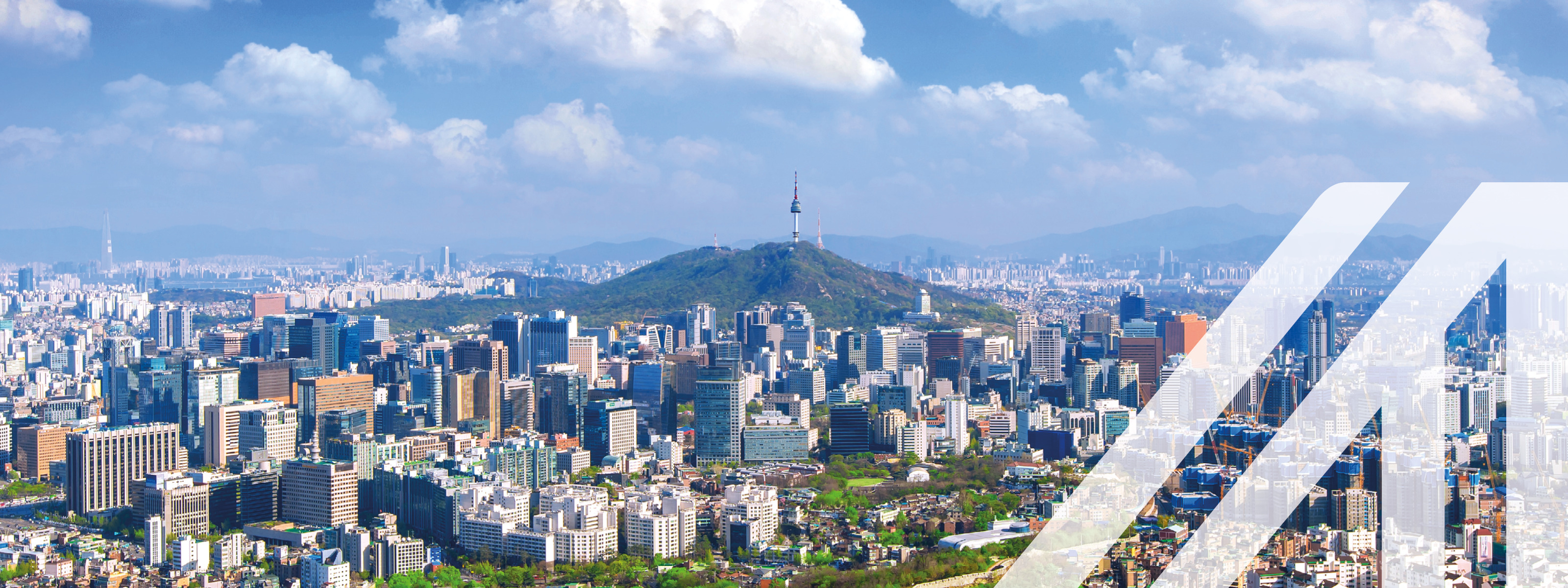 Blick auf das Stadtbild und den Seoul Tower in Seoul, Südkorea, unter blauem Himmel mit einigen Wolken. Über das Bild wurde ein weißes Austria A gelegt.
