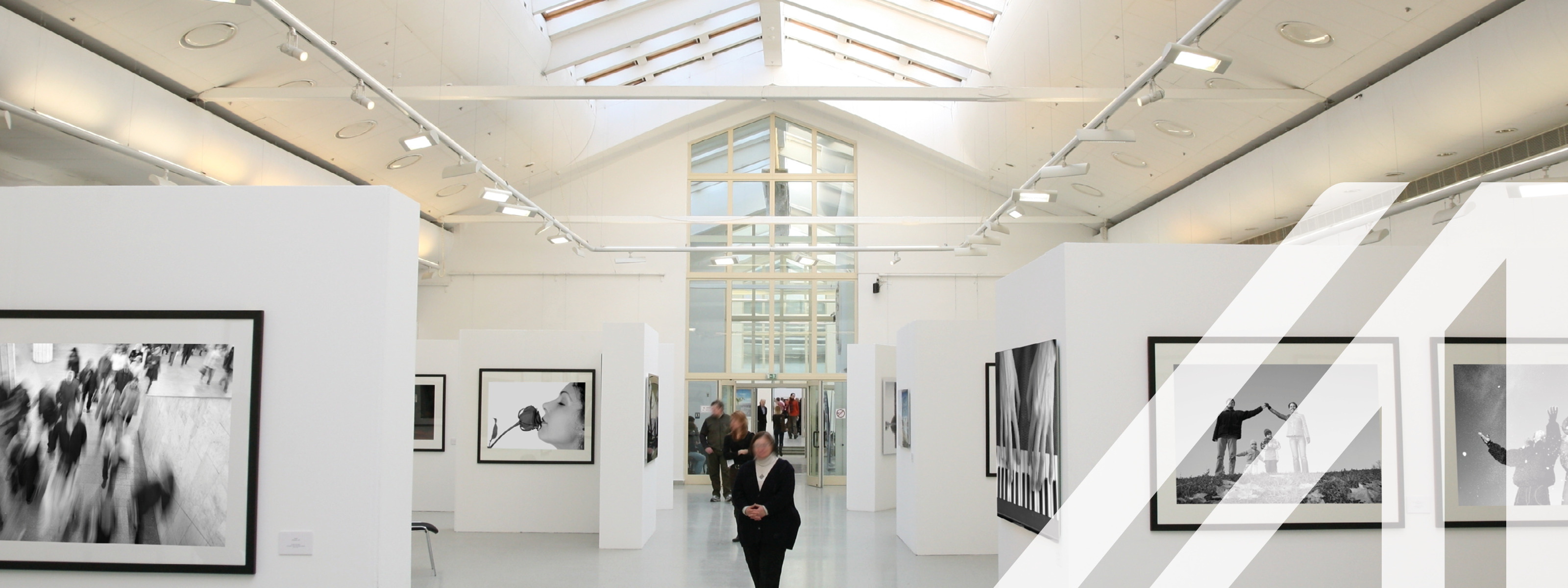 Schwarz-Weiß-Fotoausstellung in einer weißen Galerie mit Deckenfenstern