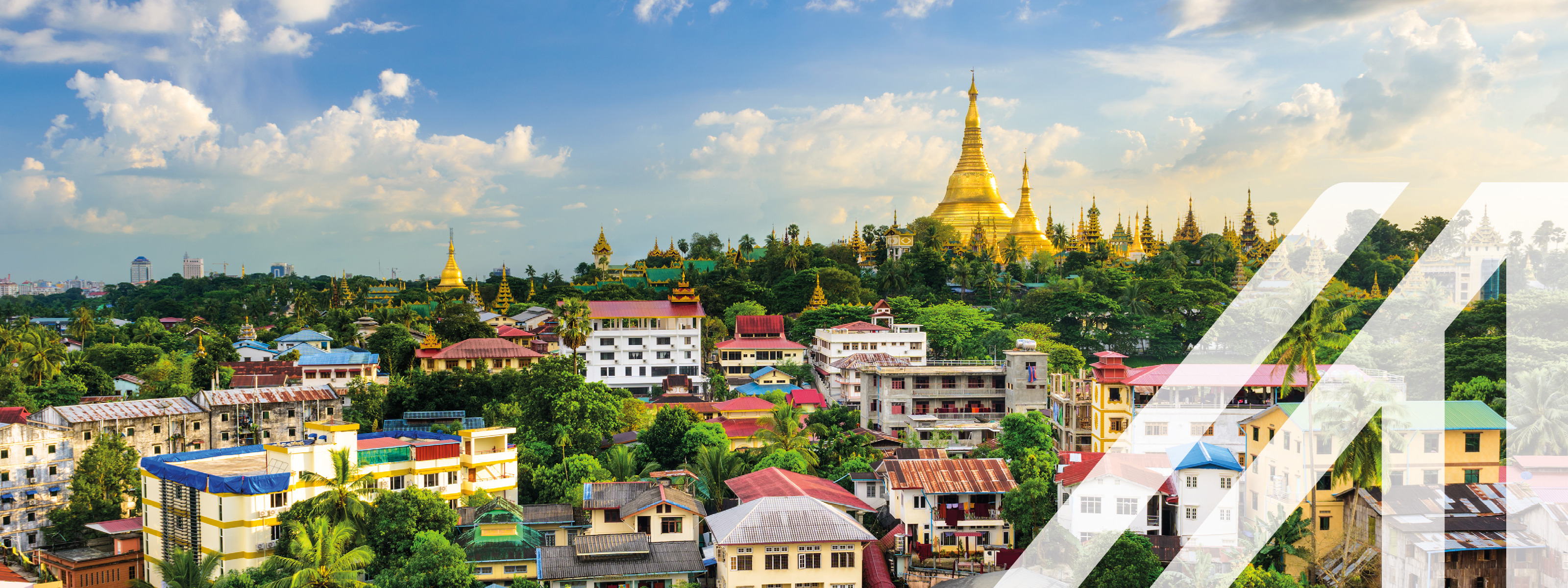 Blick auf Yangon, Hauptstadt von Myanmar. Bunte Häuser und grüne Wälder im Vorderund, im Hintergrund eine goldene Pagode 