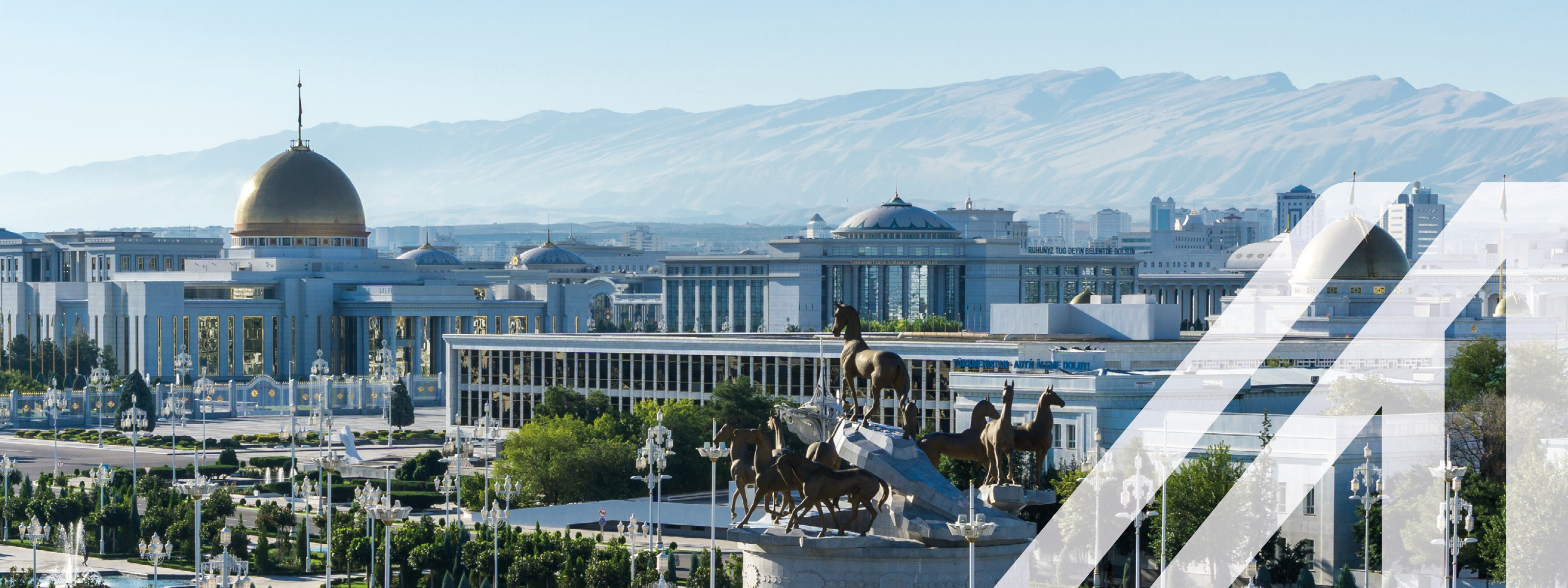 Blick auf den Präsidentenpalast (Oguzhan) mit goldener Kuppel und Pferde-Statue und Bergkette im Hintergrund in Ashkhabat Turkmenistan.
