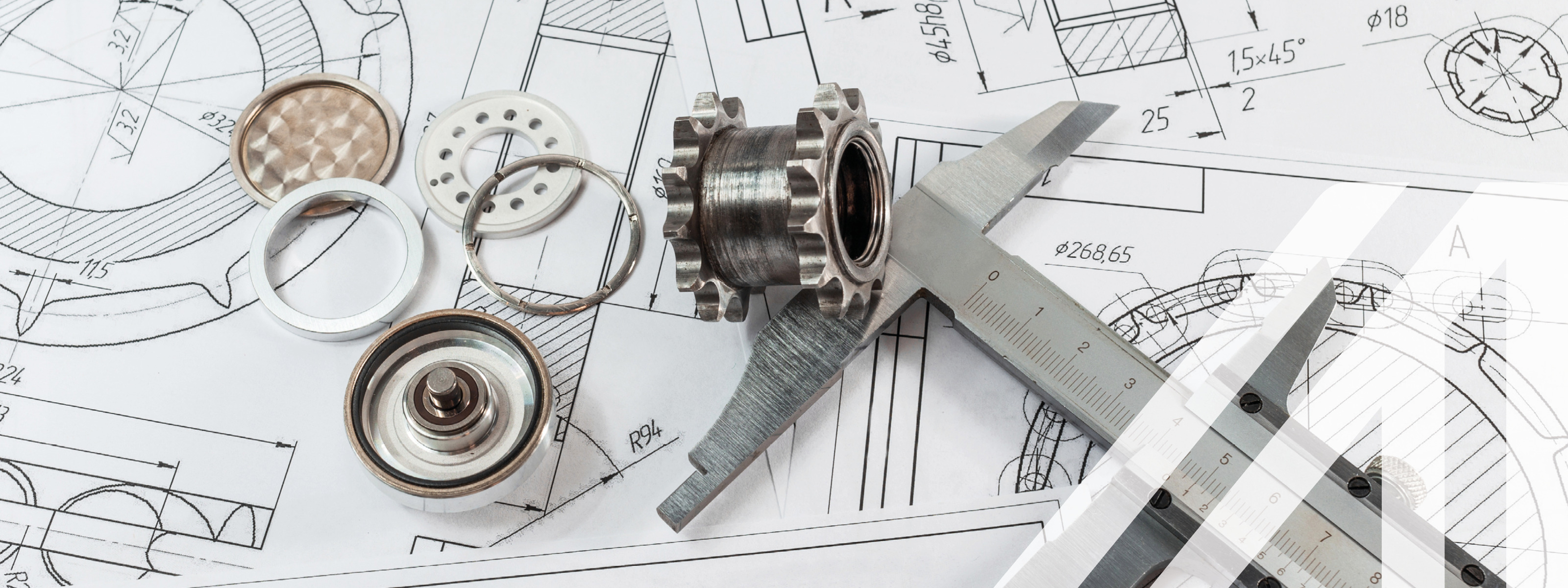 Technische Zeichnung, darüber liegen Getriebe und Bremssattelteile aus Stahl.