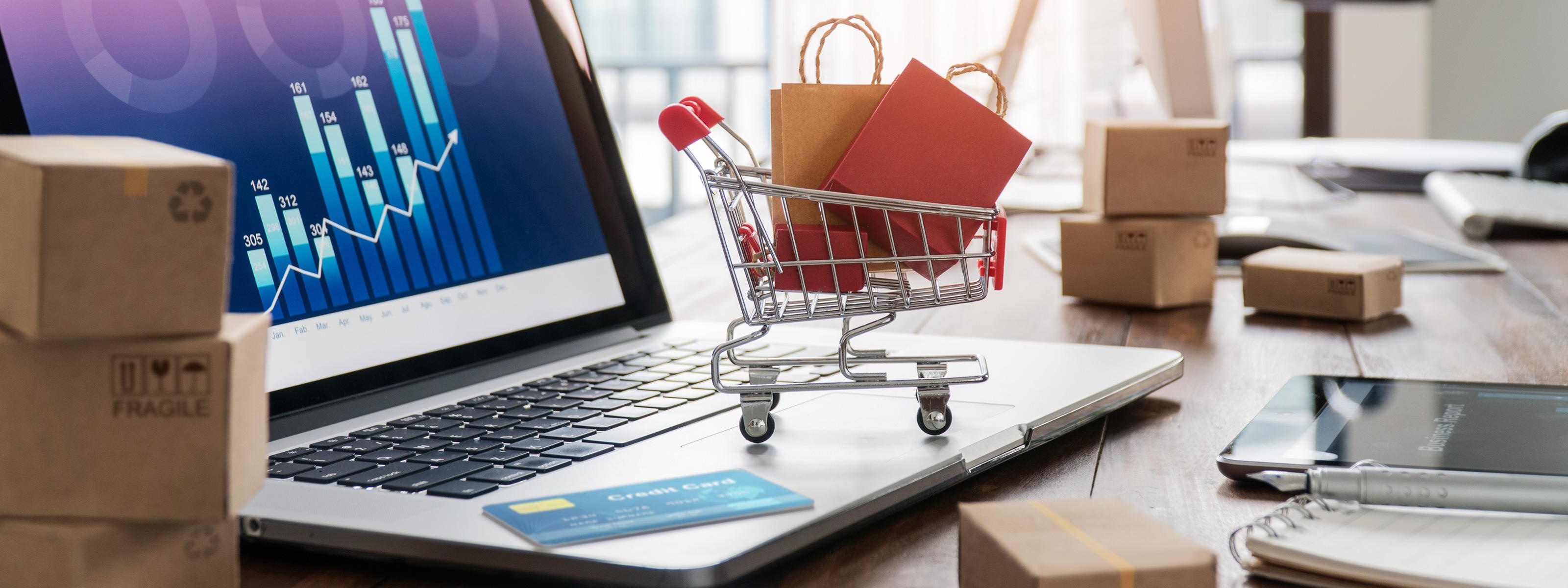 Laptop mit Baklendiagramm auf dem Bildschirm und Miniatur-Einkaufswagen auf der Tastatur 