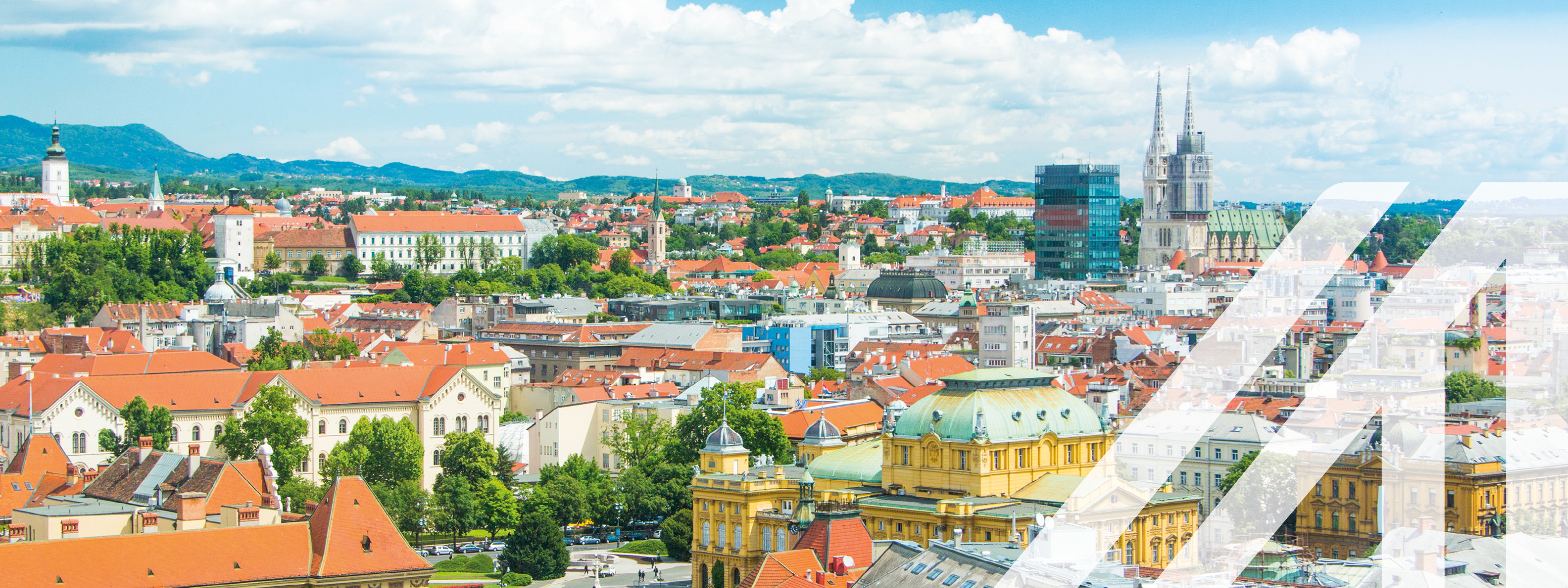 Panoramablick auf die roten Dächer der historischen Häuser im Zentrum von Zagreb mit der katholischen Kathedrale, der Himmel mit einigen Wolken ist blau