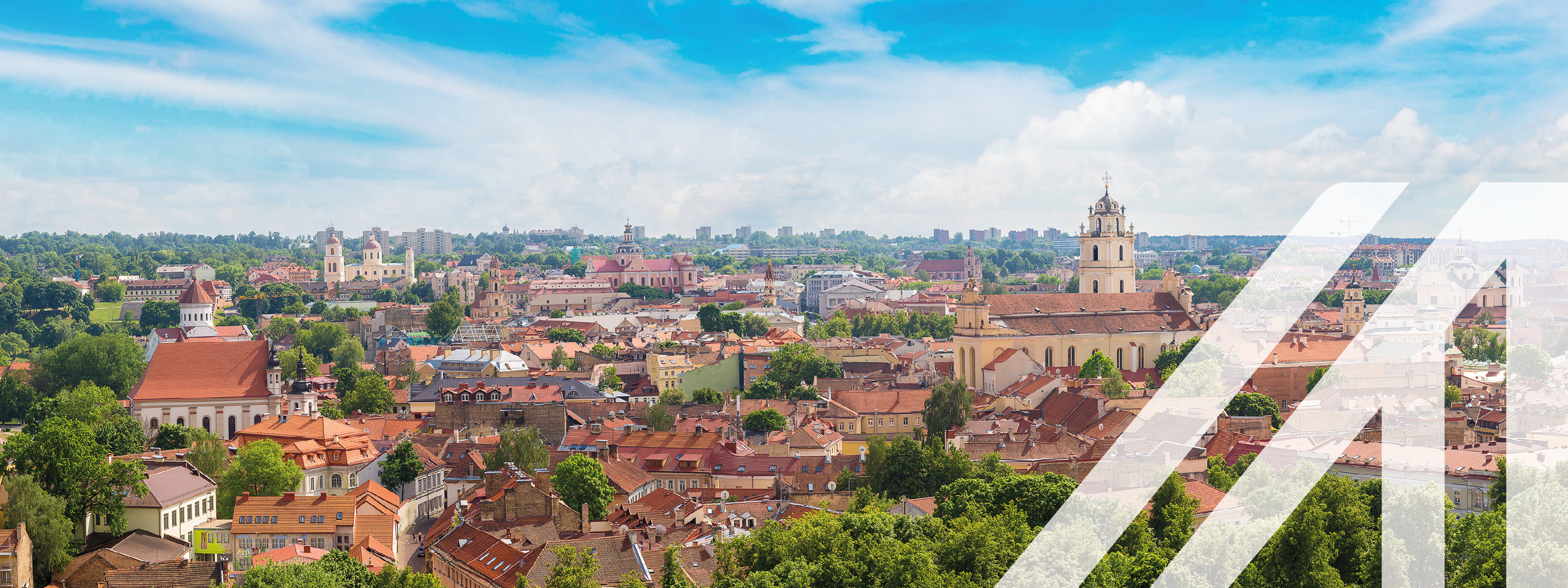 Stadtbild von Vilnius mit vielen Bäumen und roten Häusern, im Hintergrund sieht man eine Kirche