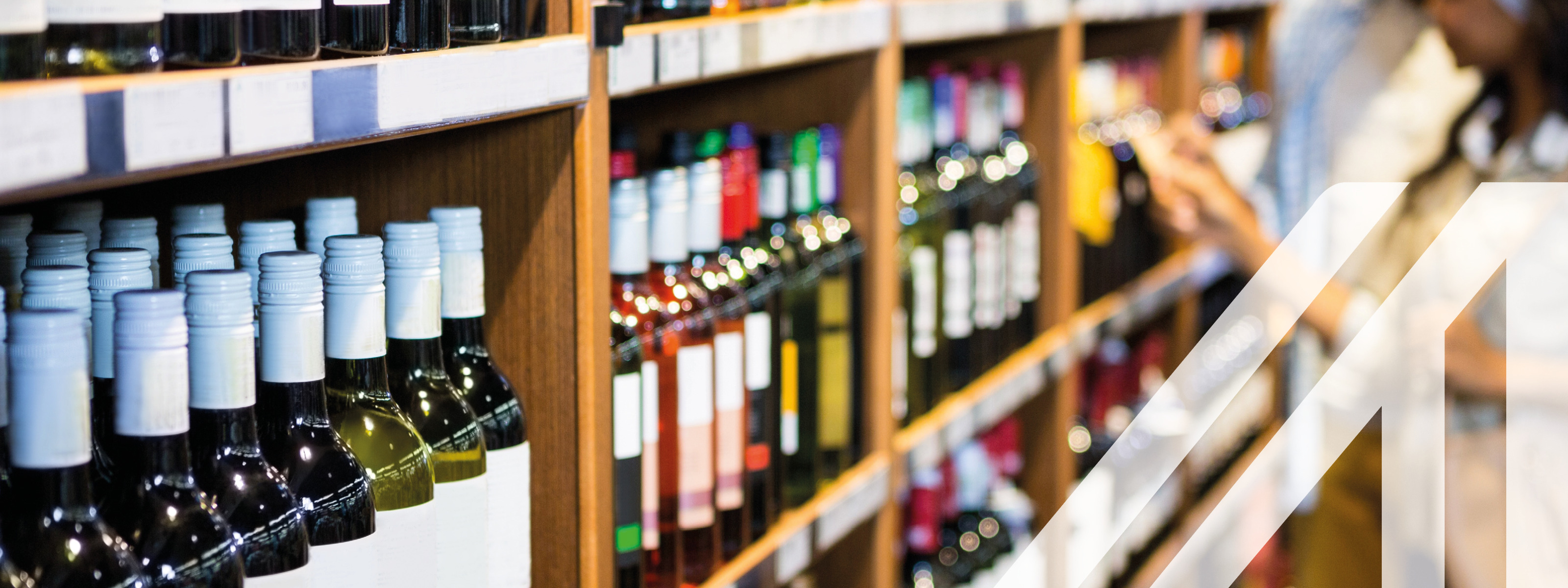 Pärchen vor Weinregal voller Flaschen bei der Auswahl einer Weinflasche im Lebensmittelgeschäft 