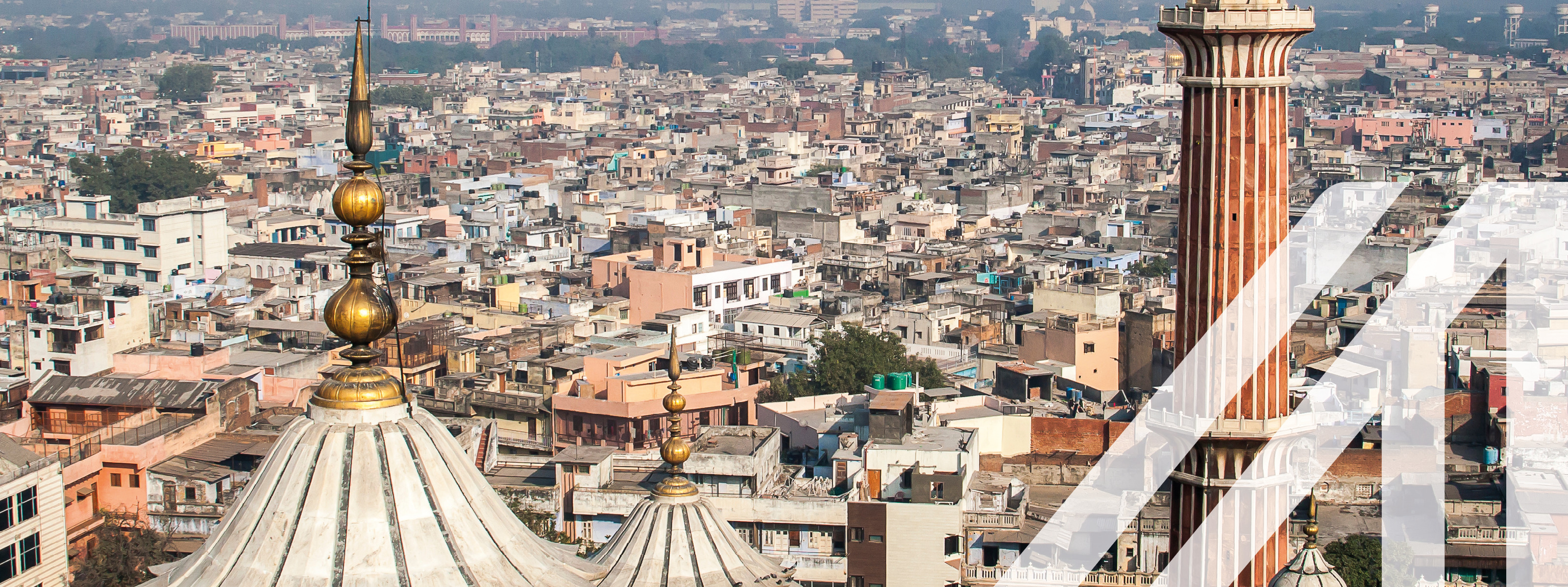 Panoramablick auf New Delhi mit vielen Häusern, im Vordergrund sieht man das Minarett und die Kuppel der Jama Masjid Moschee