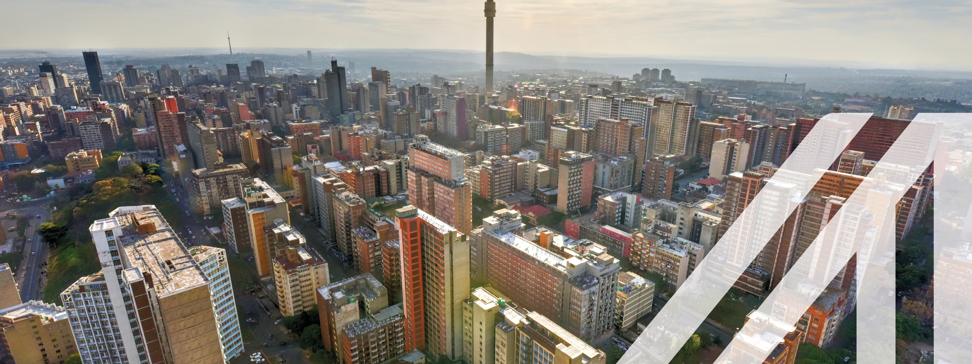 Stadtansicht von Johannesburg: Blick von oben auf zahlreiche bunte Wolkenkratzer, darunter der Hillbrow Tower in der Hauptstadt von Südafrika