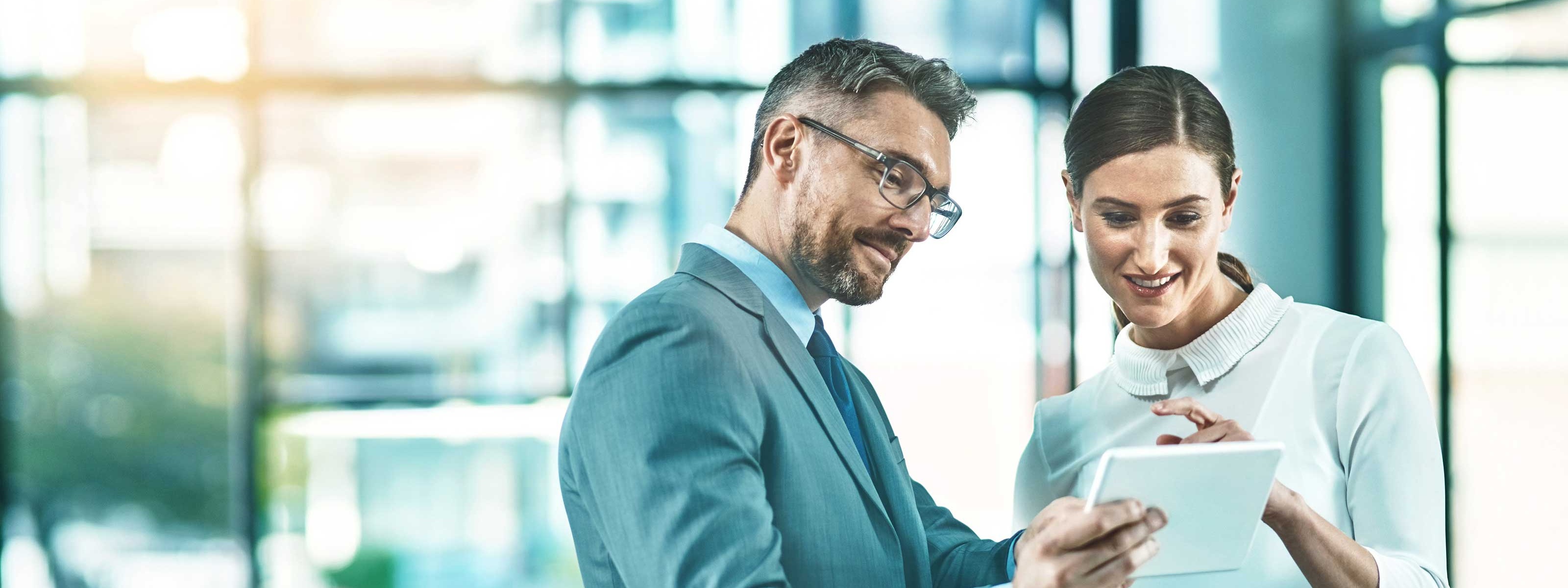 Zwei Personen stehen nebeneinander und schauen auf ein Tablet
