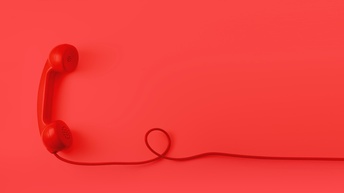 Roter Telefonhörer mit rotem Kabel eine Schlaufe bildend vor rotem Hintergrund