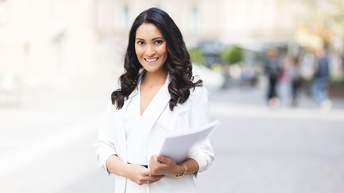 Eine lächelnde Frau, die Papierunterlagen hält.