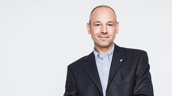 Person im Anzug vor weißem Hintergrund