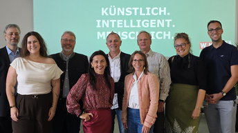 Gruppenbild von Frauen und Männern, im Hintergrund sieht man den Schriftzug 