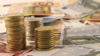 Mehrere Euro-Geldscheine auf denen Türmchen von Euro-Münzen platziert sind.