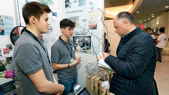 Drei Personen bei Messestand stehend