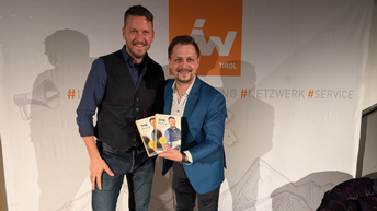 Zwei Männer halten Broschüren in die Kamera