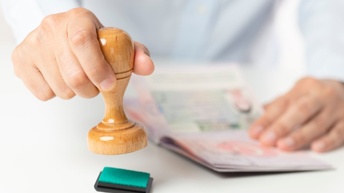 Hand hält Stempel und stempelt Formular ab